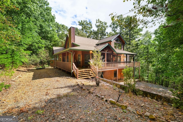 view of home's exterior featuring gravel driveway, a shingled roof, a chimney, and log veneer siding