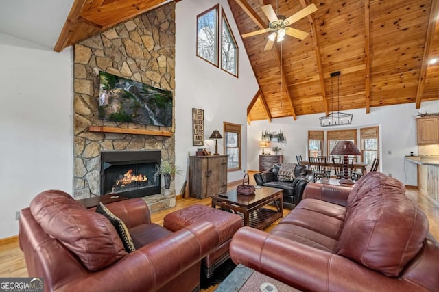 living room with light hardwood / wood-style flooring, ceiling fan, beam ceiling, high vaulted ceiling, and a fireplace