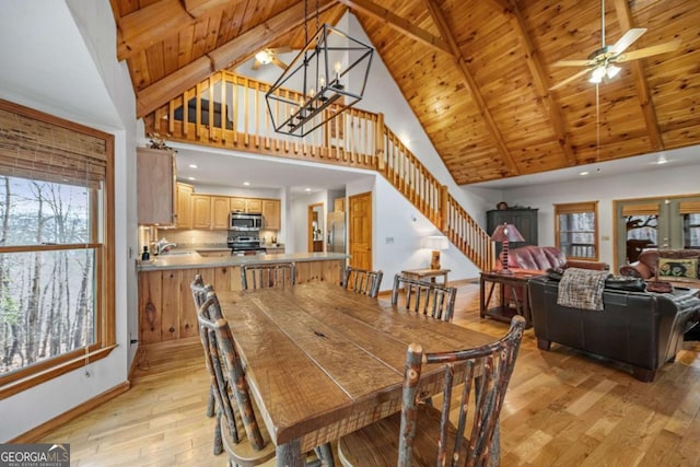 dining space featuring high vaulted ceiling, sink, wood ceiling, beam ceiling, and light hardwood / wood-style flooring