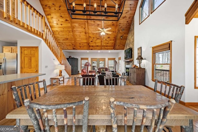 dining space with ceiling fan, light hardwood / wood-style flooring, high vaulted ceiling, and a healthy amount of sunlight