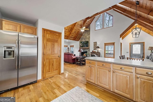 kitchen featuring light hardwood / wood-style flooring, beam ceiling, stainless steel refrigerator with ice dispenser, a stone fireplace, and light brown cabinets