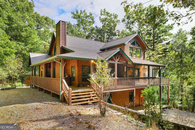 view of front of home with a porch, roof with shingles, a chimney, and faux log siding