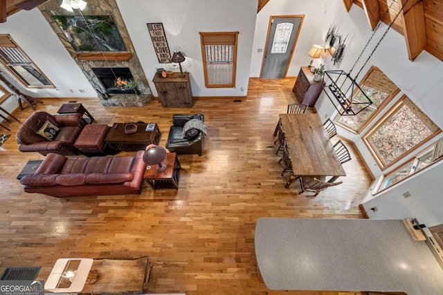 living room featuring hardwood / wood-style flooring, a fireplace, and a towering ceiling