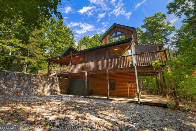 380 Oak Ridge Way, Morganton, GA 30560 - back of house featuring a deck, faux log siding, a garage, a chimney, and gravel driveway