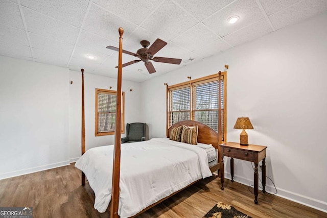 bedroom featuring hardwood / wood-style flooring, a drop ceiling, and ceiling fan