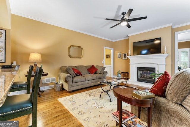 256 Allie Dr, Mcdonough, GA 30252 - living area featuring crown molding, visible vents, a ceiling fan, a glass covered fireplace, and wood finished floors