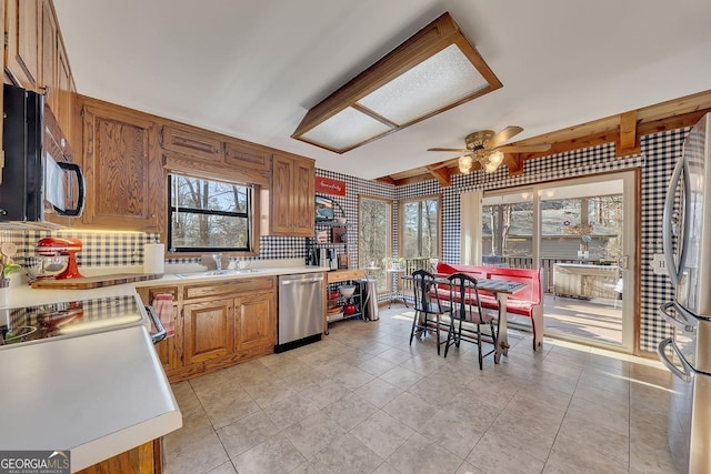 kitchen with stainless steel appliances, brown cabinets, light countertops, and a sink