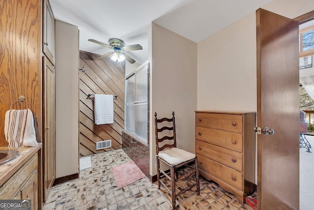 bathroom featuring a ceiling fan, a wealth of natural light, visible vents, and wood walls