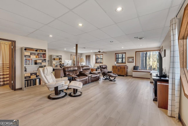 living area featuring light wood-type flooring, baseboards, and a drop ceiling