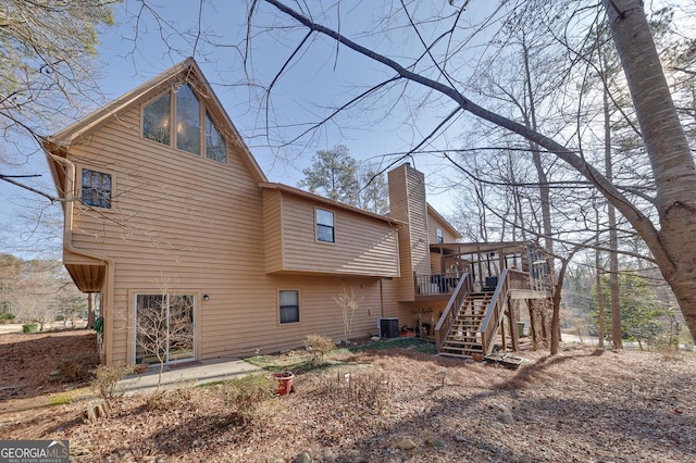 back of property with a sunroom, central air condition unit, a chimney, and stairs