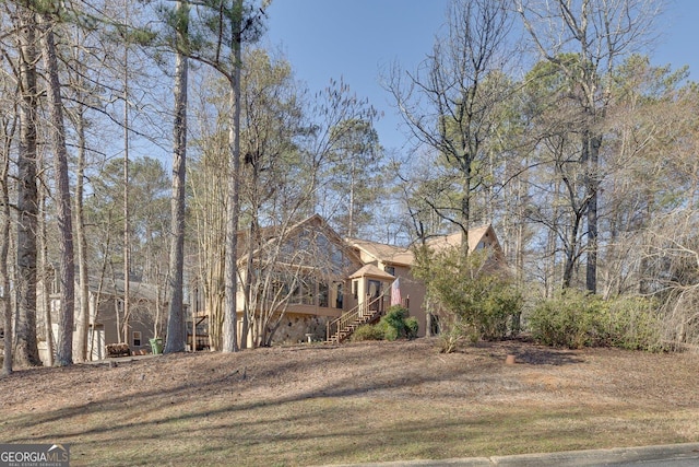 view of front of home with stairway, a front lawn, and stucco siding