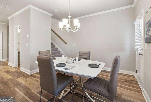 dining area featuring visible vents, ornamental molding, wood finished floors, a chandelier, and baseboards