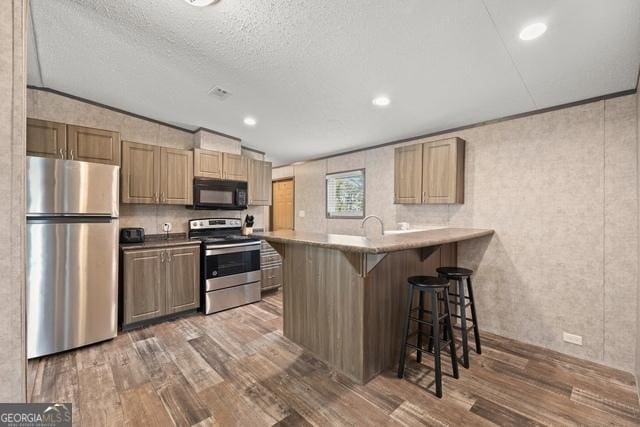 kitchen with stainless steel appliances, a breakfast bar, dark wood finished floors, and light countertops