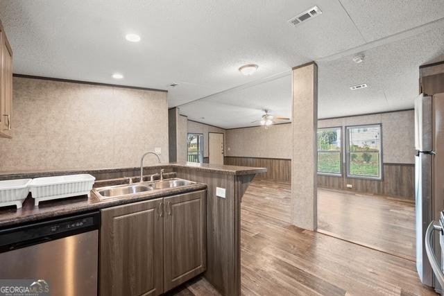 kitchen with dark countertops, visible vents, appliances with stainless steel finishes, open floor plan, and a sink