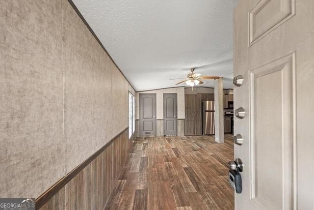 corridor featuring vaulted ceiling, a textured ceiling, and wood finished floors