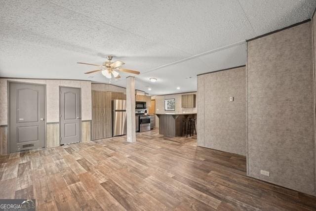 unfurnished living room featuring a ceiling fan, dark wood finished floors, and a textured ceiling