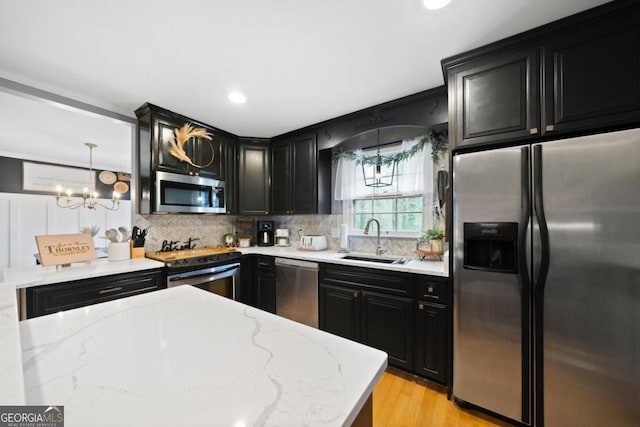 kitchen featuring pendant lighting, sink, stainless steel appliances, light stone countertops, and decorative backsplash