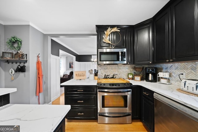 kitchen featuring light stone countertops, ornamental molding, appliances with stainless steel finishes, and decorative backsplash