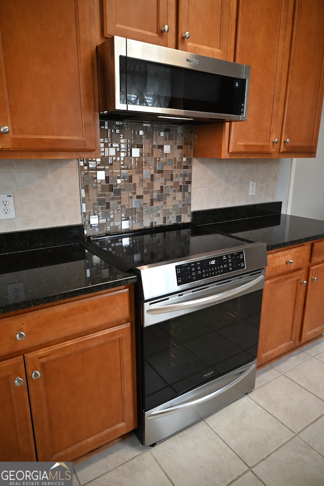 kitchen featuring brown cabinets, dark stone counters, tasteful backsplash, and stainless steel appliances