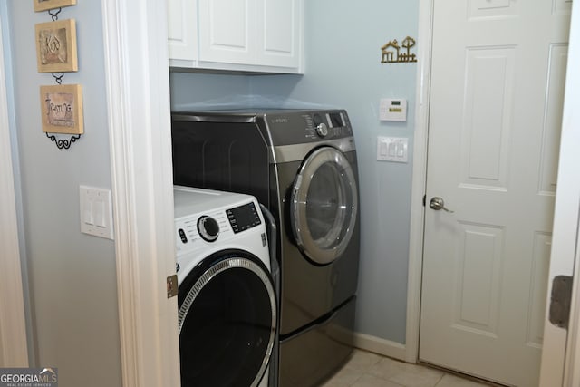 laundry area featuring light tile patterned floors, cabinet space, washing machine and dryer, and baseboards