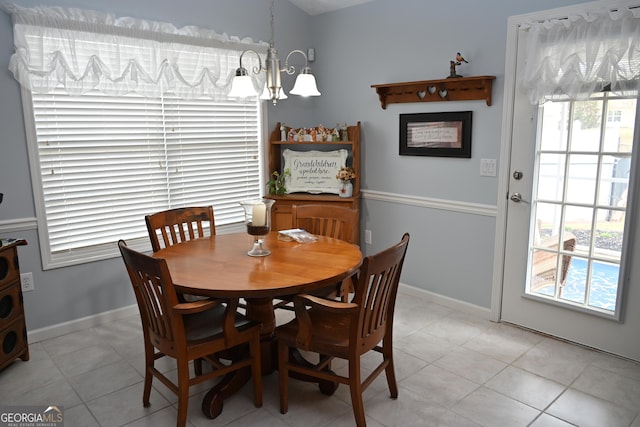 dining space with light tile patterned flooring, baseboards, and an inviting chandelier