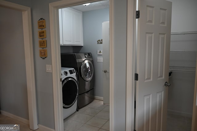 laundry room featuring washer and clothes dryer, cabinet space, baseboards, and light tile patterned floors