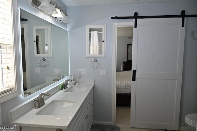 full bathroom featuring double vanity, a sink, toilet, and ensuite bathroom