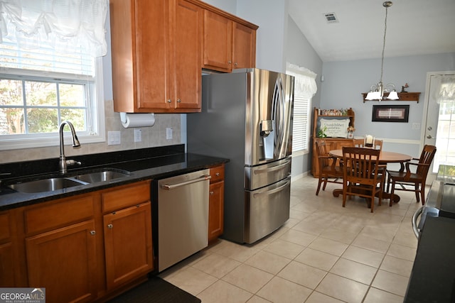 kitchen with sink, decorative light fixtures, vaulted ceiling, light tile patterned floors, and appliances with stainless steel finishes