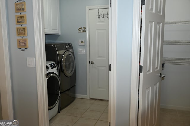 laundry room featuring cabinets, washer and dryer, and light tile patterned floors