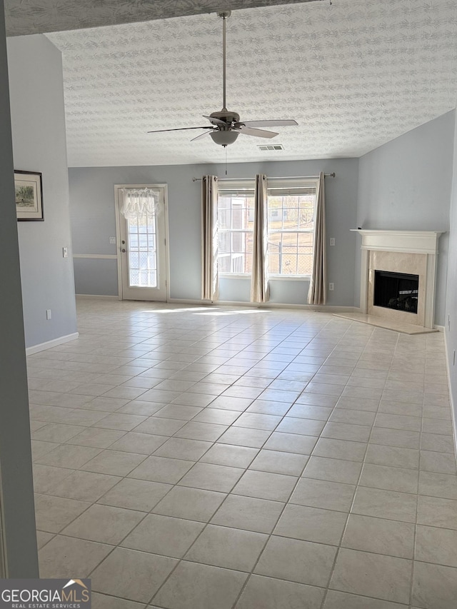 unfurnished living room with plenty of natural light, visible vents, a ceiling fan, and light tile patterned floors