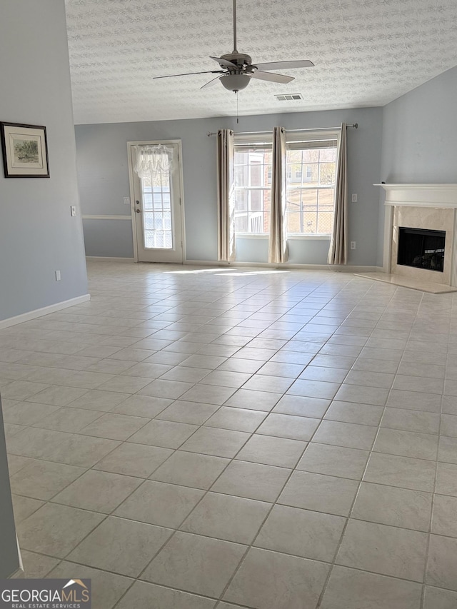 unfurnished living room with light tile patterned floors, a textured ceiling, a healthy amount of sunlight, and ceiling fan