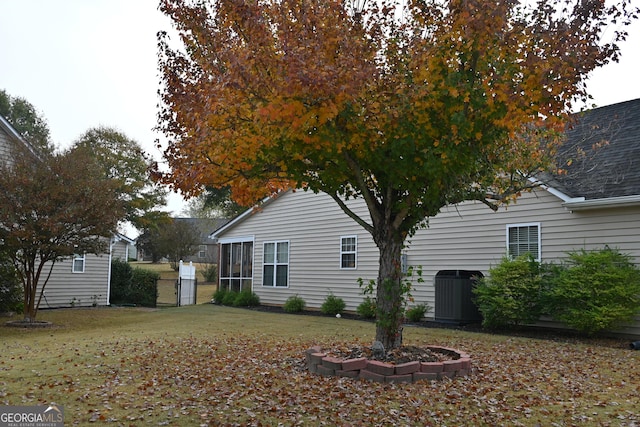 view of side of property with central AC unit and a yard