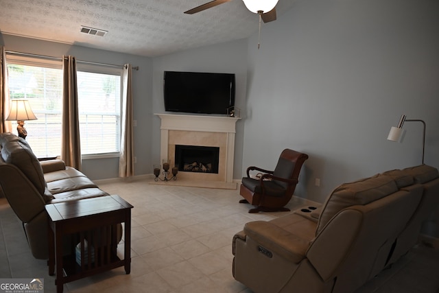 living room with ceiling fan, lofted ceiling, a premium fireplace, and a textured ceiling