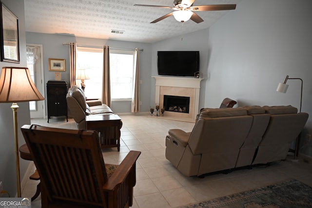 tiled living room with ceiling fan, lofted ceiling, a textured ceiling, and a fireplace