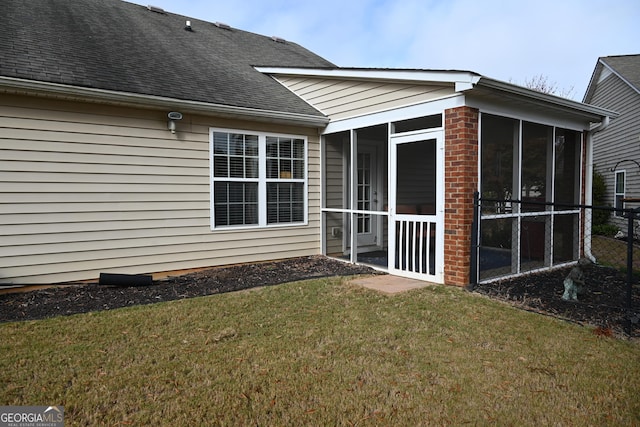 back of property with a sunroom, a shingled roof, and a yard