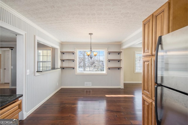 unfurnished dining area featuring crown molding, dark hardwood / wood-style floors, a textured ceiling, and a notable chandelier