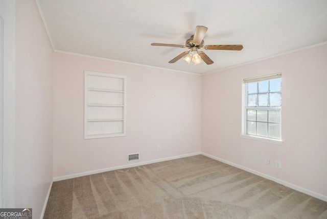 empty room featuring crown molding, light colored carpet, ceiling fan, and built in shelves