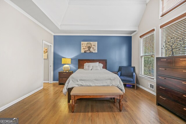 bedroom featuring baseboards, visible vents, wood finished floors, and ornamental molding