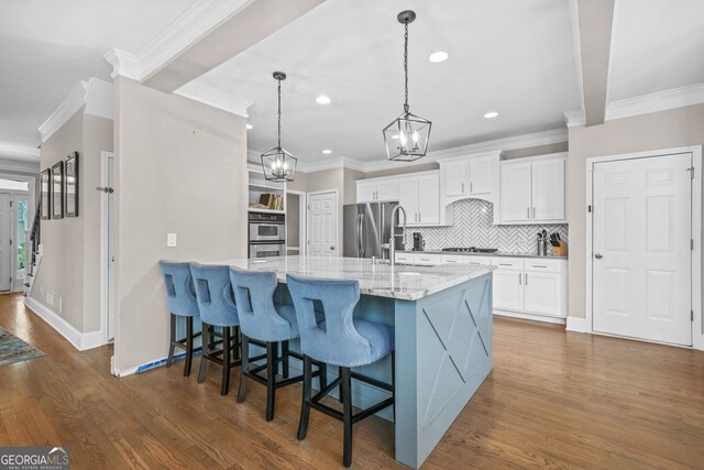 kitchen with stainless steel appliances, dark wood finished floors, white cabinetry, and a kitchen breakfast bar