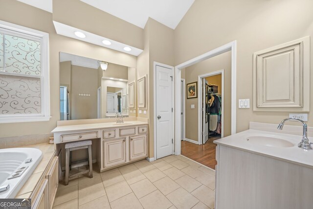 bathroom featuring tile patterned flooring, vaulted ceiling, two vanities, and a sink