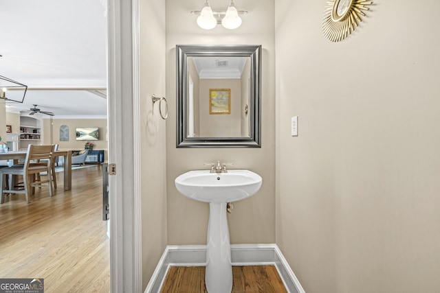 bathroom featuring ceiling fan with notable chandelier, ornamental molding, wood finished floors, and baseboards