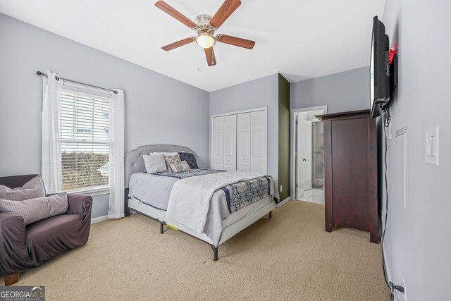 bedroom with light carpet, connected bathroom, baseboards, and a ceiling fan