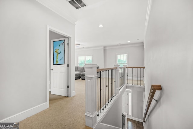 hall with baseboards, visible vents, carpet, crown molding, and an upstairs landing