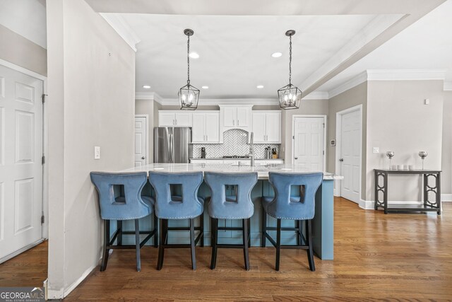 kitchen with dark wood-style flooring, backsplash, freestanding refrigerator, and white cabinets