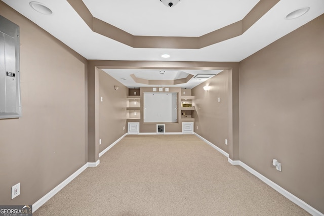 carpeted spare room with a tray ceiling and baseboards