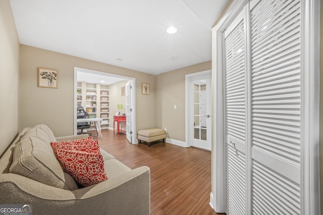 living area with baseboards, wood finished floors, and recessed lighting