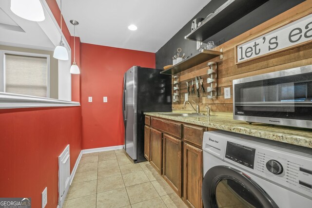 kitchen with light tile patterned floors, stainless steel appliances, open shelves, washer / clothes dryer, and a sink