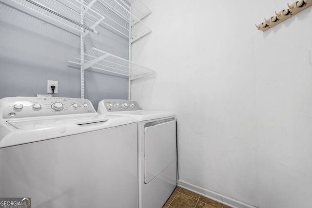 washroom with laundry area, dark tile patterned floors, washing machine and clothes dryer, and baseboards