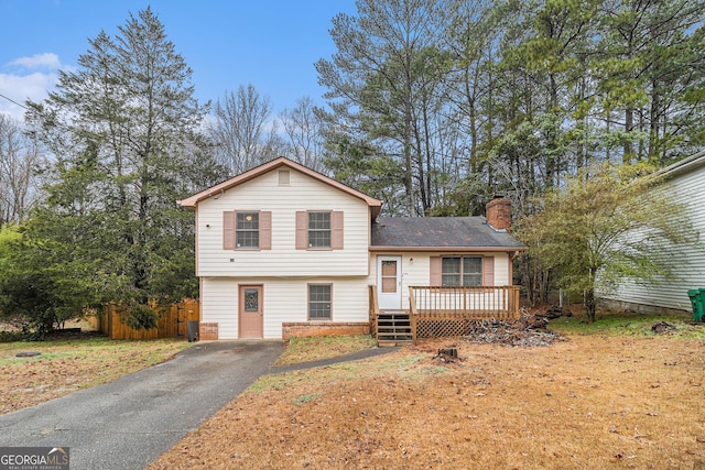 split level home with a wooden deck and a front yard