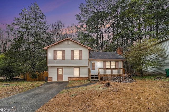 split level home with a wooden deck and a yard